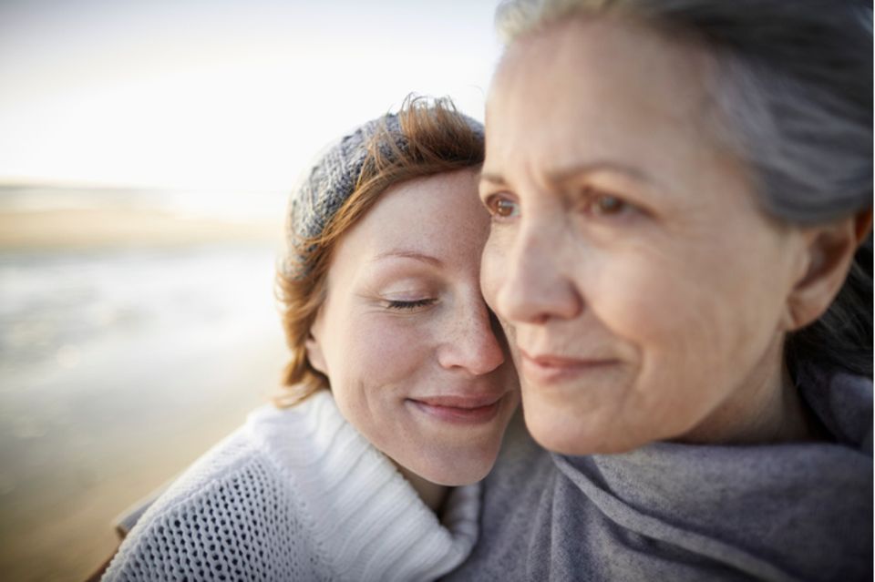 Mutter und Tochter umarmen sich am Strand 1.499