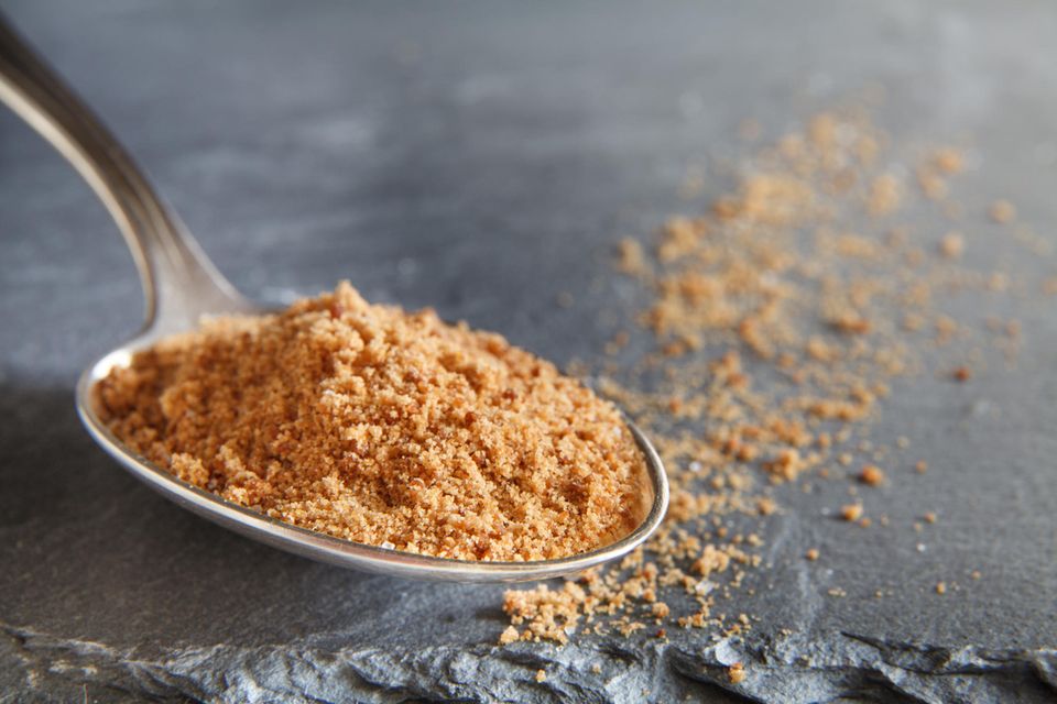 Ein Löffel mit braunem, groben Kokosblütenzucker. Ein Löffel mit braunem, groben Kokosblütenzucker.