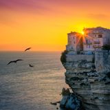 Blick auf Häuser, die über dem Meer auf einer Klippe stehen im Sonnenuntergang