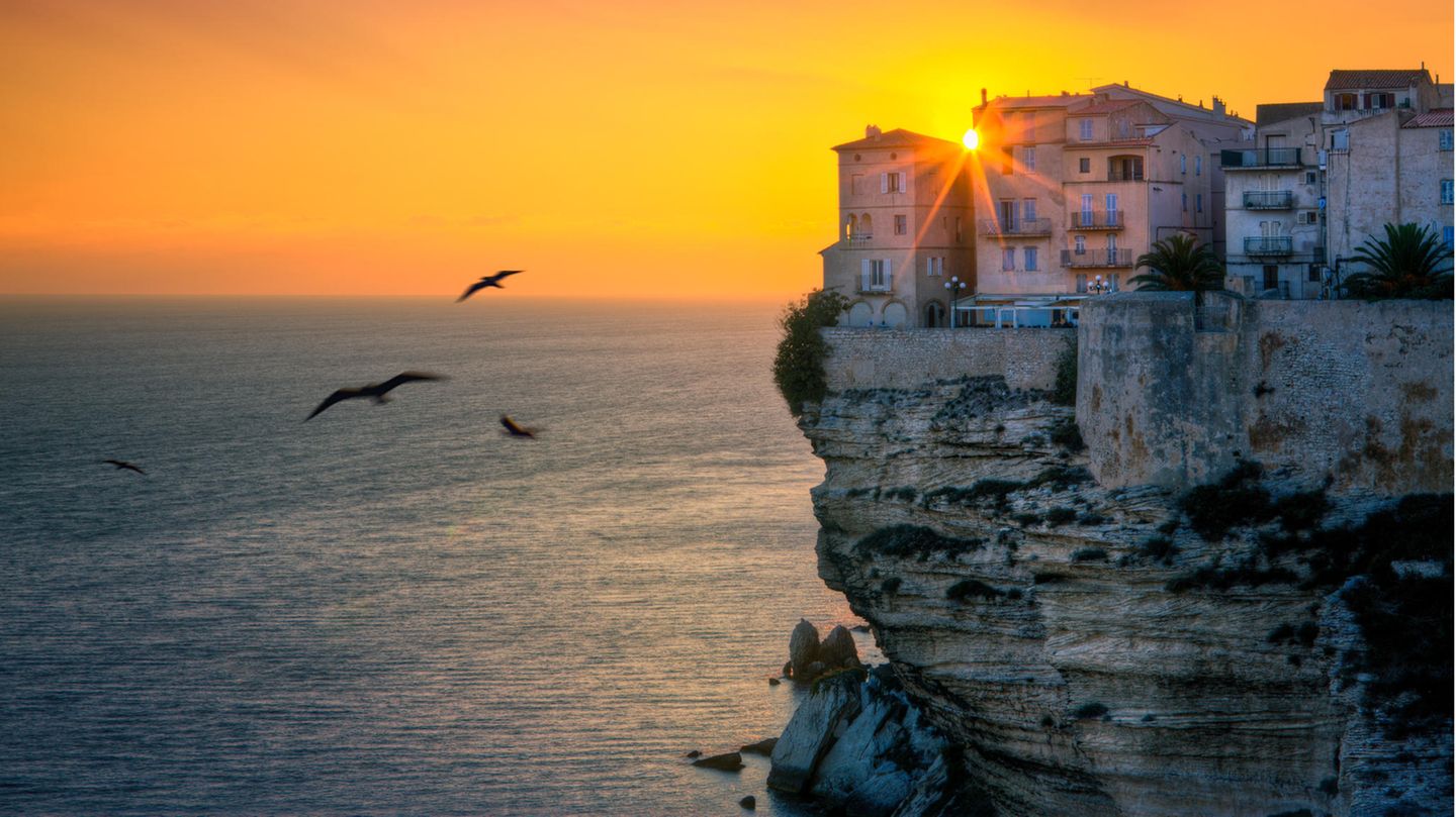 Blick auf Häuser, die über dem Meer auf einer Klippe stehen im Sonnenuntergang