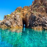 Rötlich schimmerndes Felsentor im türkisen Meer