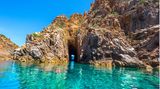 Rötlich schimmerndes Felsentor im türkisen Meer