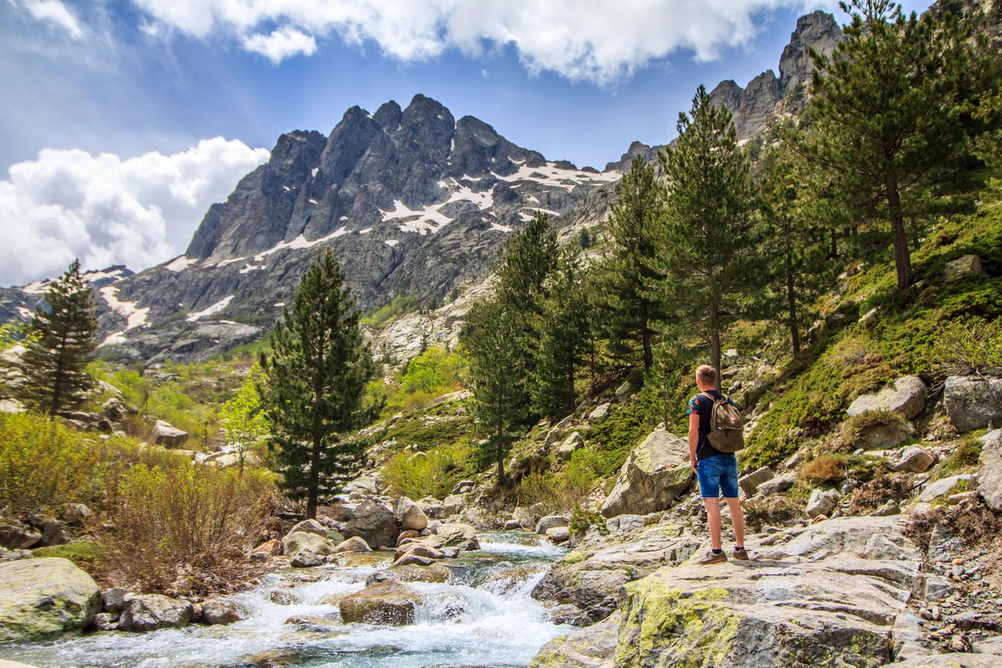 Parc naturel régional de Corse - Wildes Herz Wanderer steht an einem wilden Fluss mit Blick auf Bergspitzen