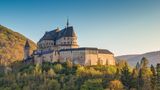 Schloss Vianden umgeben von Bäumen bei blauem Himmel