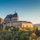 Schloss Vianden umgeben von Bäumen bei blauem Himmel