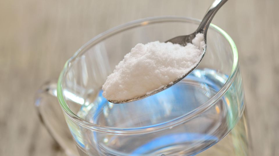Löffel mit Natron über einem Wasserglas