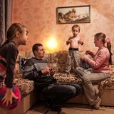 Eltern sind mit ihren zwei Kindern in einem Wohnzimmer