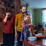 Mutter und Vater stehen mit der Tochter in der Küche vor einem Tisch, auf dem Essen steht