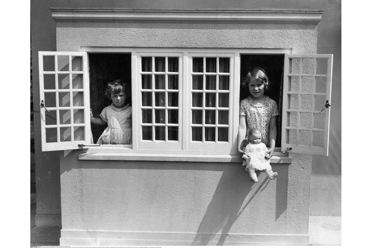 ZWEI SCHWESTERN Elisabeth und die vier Jahre jüngere Margaret werden von Privatlehrern unterrichtet und haben als Spielgefährtinnen vor allem einander. Hier posieren sie in einem Minicottage – einem Geschenk der Bevölkerung von Wales zu Elisabeths sechstem Geburtstag. Daheim haben die Geschwister ein ganzes Stockwerk für sich.
