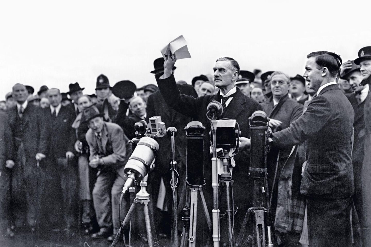 Nach seiner Rückkehr aus München, wo er mit Adolf Hitler ein Abkommen ausgehandelt hat, schwenkt der britische Premierminister Neville Chamberlain am 30. September 1938 ein Stück Papier, das ihm zufolge den "Frieden für unsere Zeit" bedeute. Als Zugeständnis an Hitler hat Chamberlain kurz zuvor dem Deutschen Reich erlaubt, das Sudetenland zu annektieren. Um dieses Gebiet, das die mehrheitlich von Deutschen bewohnten Teile der Tschechoslowakei umfasst, unter seine Kontrolle zu bringen, hatte Hitler mit Krieg gedroht und die Briten in Schrecken versetzt. Nach Chamberlains Mission ist die Angst vorerst verflogen. Doch der Premierminister irrt: Hitler hat seine Eroberungspläne nicht aufgegeben. Im März 1939 befiehlt er den Einmarsch in Prag. Der Krieg wird kommen
