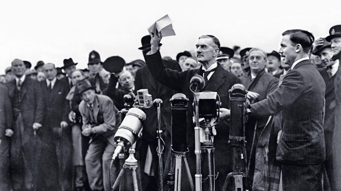 DIPLOMATISCHER SCHEINSIEG Nach seiner Rückkehr aus München, wo er mit Adolf Hitler ein Abkommen ausgehandelt hat, schwenkt der britische Premierminister Neville Chamberlain am 30. September 1938 ein Stück Papier, das ihm zufolge den "Frieden für unsere Zeit" bedeute. Als Zugeständnis an Hitler hat Chamberlain kurz zuvor dem Deutschen Reich erlaubt, das Sudetenland zu annektieren. Um dieses Gebiet, das die mehrheitlich von Deutschen bewohnten Teile der Tschechoslowakei umfasst, unter seine Kontrolle zu bringen, hatte Hitler mit Krieg gedroht und die Briten in Schrecken versetzt. Nach Chamberlains Mission ist die Angst vorerst verflogen. Doch der Premierminister irrt: Hitler hat seine Eroberungspläne nicht aufgegeben. Im März 1939 befiehlt er den Einmarsch in Prag. Der Krieg wird kommen