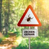 Schild im Wald warnt vor Zecken