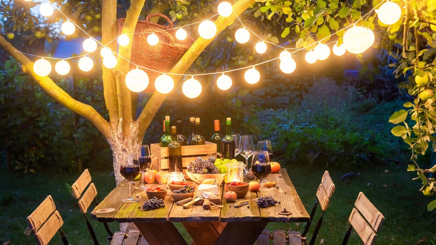 Ein reichlich gedeckter Tisch im Garten unter einer Lichterkette.