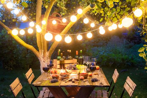 Ein reichlich gedeckter Tisch im Garten unter einer Lichterkette.