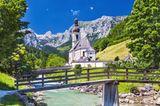 Die Pfarrkirche St. Sebastian mit Ramsauer Ache und Ertlsteg im Vordergrund sowie der Reiter Alpe im Hintergrund