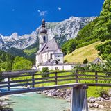 Die Pfarrkirche St. Sebastian mit Ramsauer Ache und Ertlsteg im Vordergrund sowie der Reiter Alpe im Hintergrund