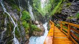 Blick auf die Klamm mit rauschendem Wildbach und Wasserfällen sowie dem Holzstieg, der hindurch führt