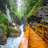 Blick auf die Klamm mit rauschendem Wildbach und Wasserfällen sowie dem Holzstieg, der hindurch führt