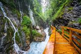 Blick auf die Klamm mit rauschendem Wildbach und Wasserfällen sowie dem Holzstieg, der hindurch führt