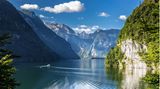 Blick auf die glatte Oberfläche des Königsees auf dem ein Boot gerade seine Kreise zieht