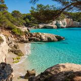 Abgeschiedene, bescheidene Schwester des bekannten Strands Cala Mitjana. Nur ein kleines Stück weiter, besticht der Strand auch mit feinem Sand und türkisblauem Wasser.  Wegbeschreibung: Von Ferreríes auf der Me-22 nach Süd- westen Richtung Küste bis zum Parkplatz nach 6 km links (vor dem Kreisverkehr). Nach rechts (der Me-22 zugewandt) zum blauen Fußgängerschild und dem Weg 250 m folgen, dann rechts und nach 250 m bei der Kreuzung links halten Richtung Playa, Platja, Beach (900 m).Wenn man sich der Cala Mitjana nähert, den Weg rechts oder an der Cala Mitjana hinten die Holzstufen hoch, oben links, dem Weg 230 m folgen und die Stufen links zum Strand hinunter.   Erreichbarkeit: Leicht 30 Min. 