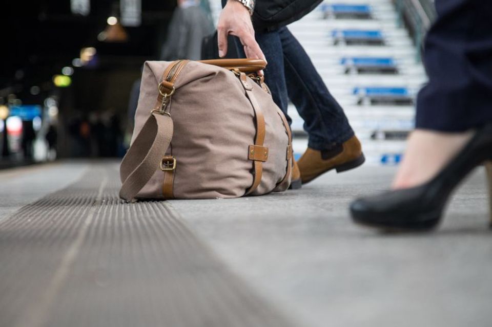 An einem Bahnhof liegt eine Reisetasche auf dem Boden