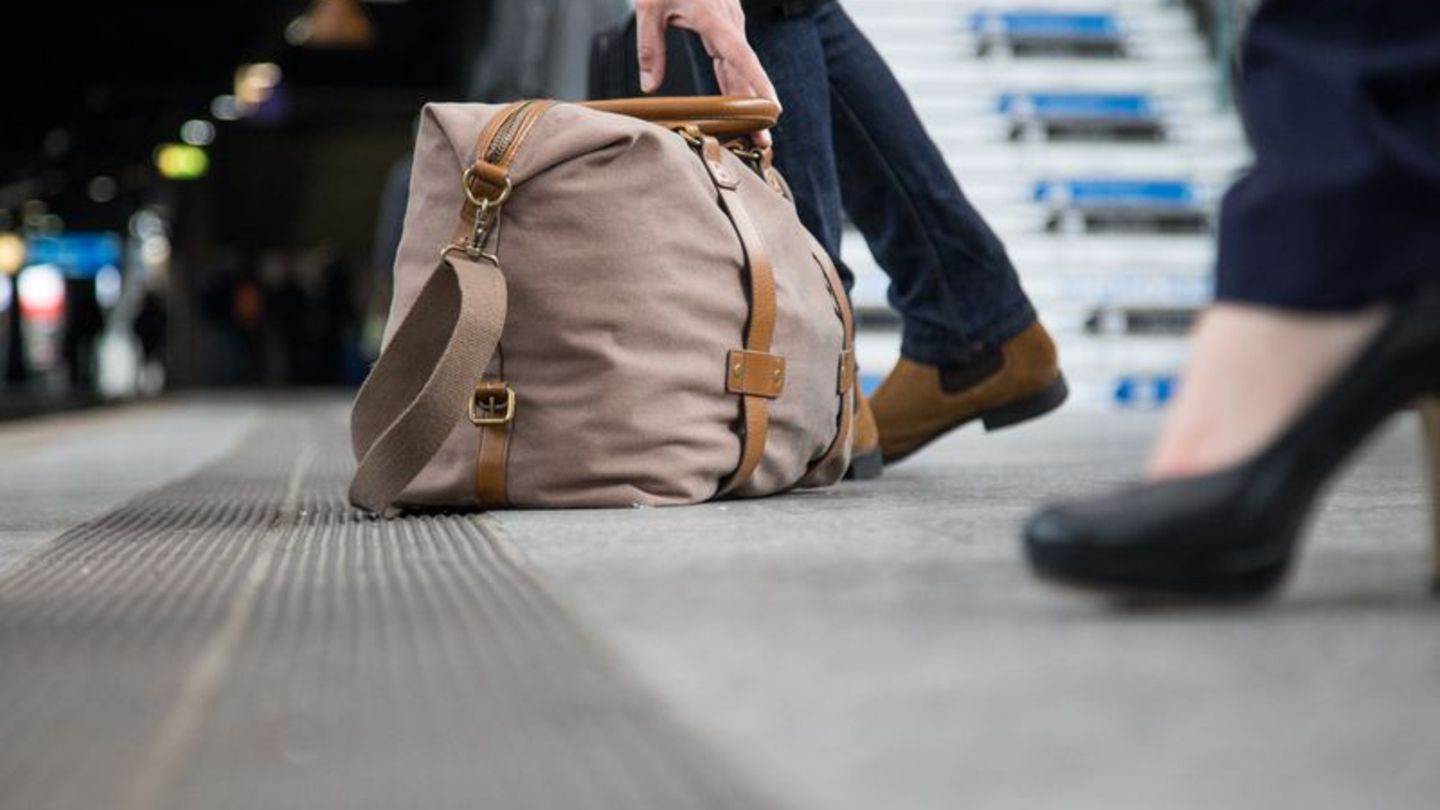 An einem Bahnhof liegt eine Reisetasche auf dem Boden