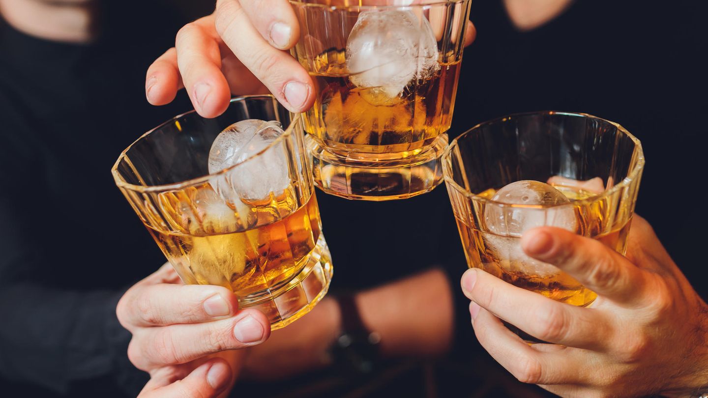 Drei Personen stoßen mit einem alkoholischen Getränk an