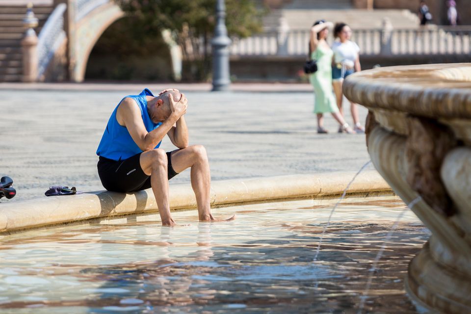 Ein Mann kühlt sich im zentralen Brunnen auf der Plaza de España in Sevilla ab. In 16 der insgesamt 17 Autonomen Gemeinschaften Spaniens sollte am Donnerstag weiterhin Hitzealarm gelten, in fünf dieser Regionen teilweise sogar Alarmstufe Rot, darunter auch in Sevilla