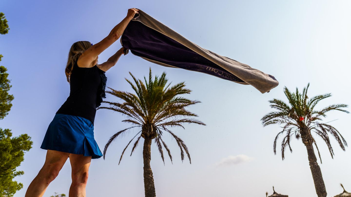 Eine Frau breitet am Strand von Alcudia ihr Handtuch aus