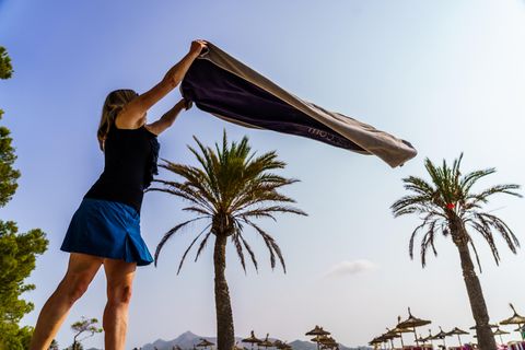 Eine Frau breitet am Strand von Alcudia ihr Handtuch aus