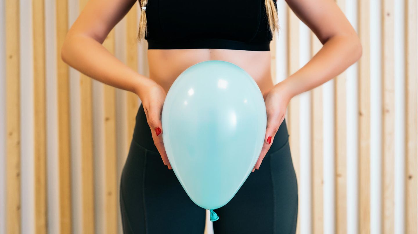 Frau hält einen Luftballon vor ihren Bauch und Schambereich