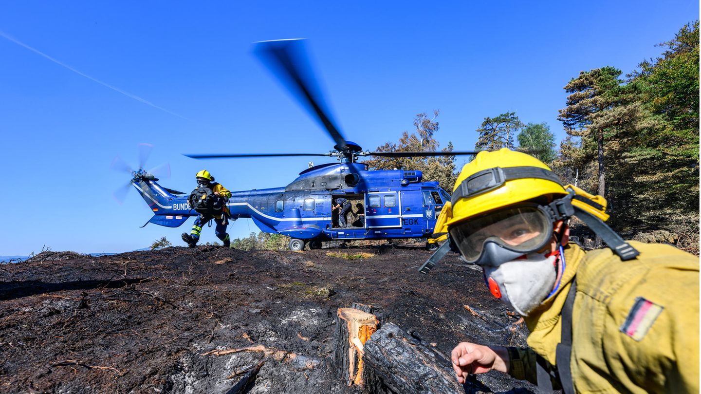 Sie werden von freiwilligen Feuerwehrleuten des Internationalen Katastrophenschutzes Deutschland unterstützt, die am Boden nach verbleibenden Glutnester suchen und diese löschen