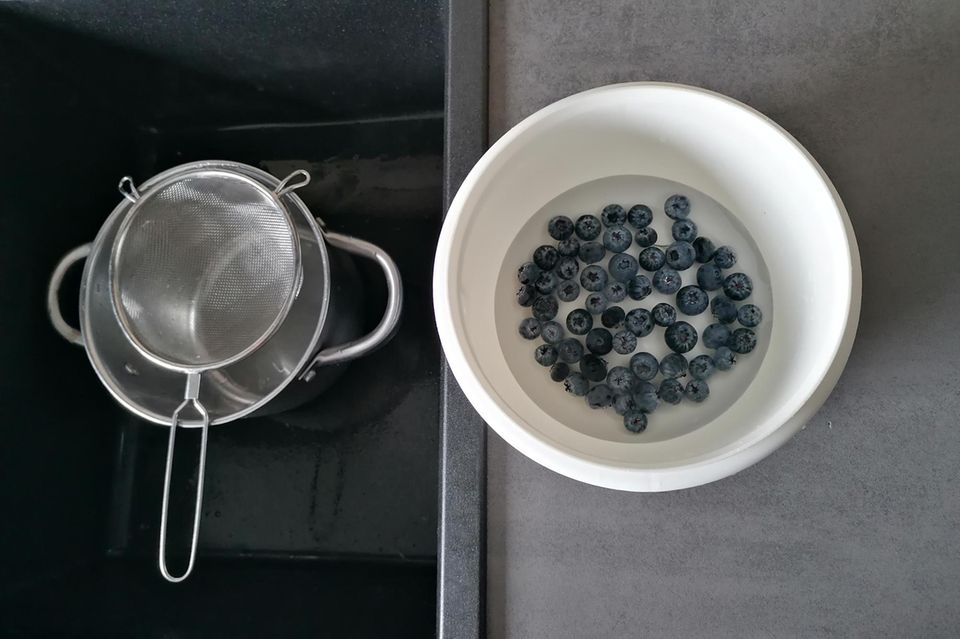 Heidelbeeren werden in Wasserschüssel gewaschen Heidelbeeren werden in Wasserschüssel gewaschen