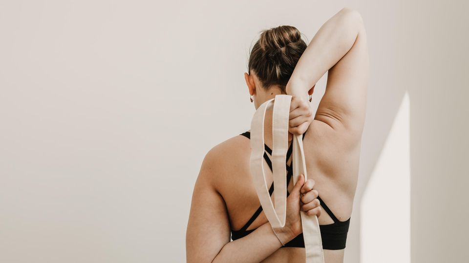 Ein Yogagurt wird als Yoga-Zubehör genutzt, um eine Dehnübung besser auszuführen. Ein Yogagurt wird als Yoga-Zubehör genutzt, um eine Dehnübung besser auszuführen.