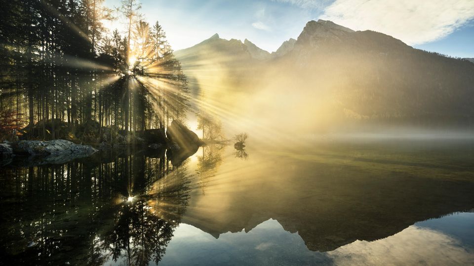 Sonnenstrahlen durchdringen den Morgendunst über dem Hintersee Sonnenstrahlen durchdringen den Morgendunst über dem Hintersee