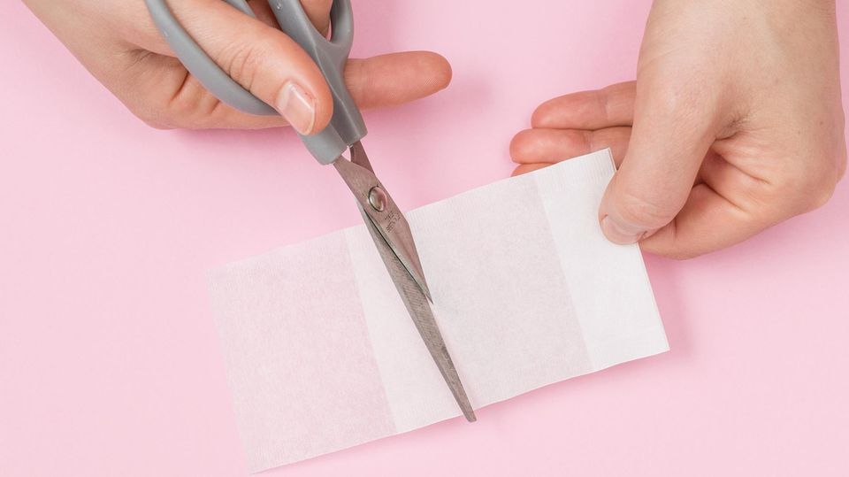 Aus einem Papierteefilter wird mit einer Schere ein Teebeutel ausgeschnitten Aus einem Papierteefilter wird mit einer Schere ein Teebeutel ausgeschnitten