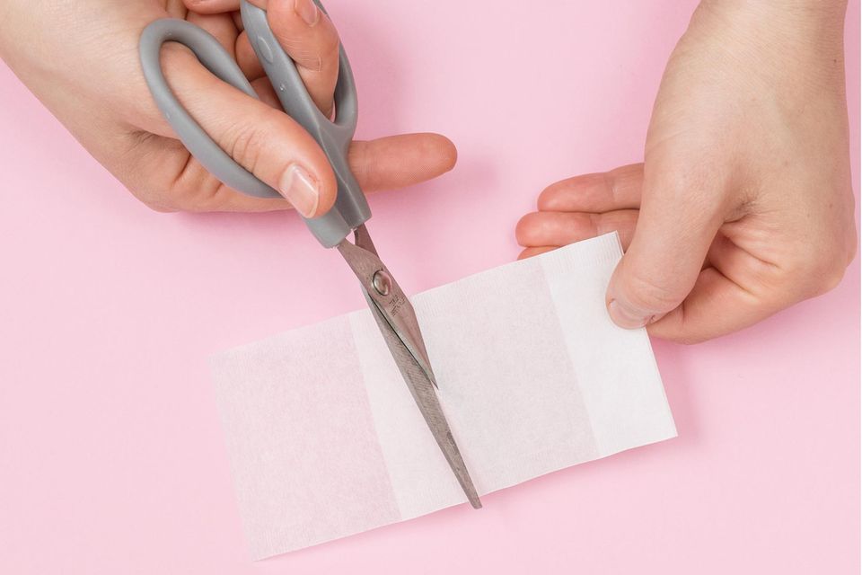 Aus einem Papierteefilter wird mit einer Schere ein Teebeutel ausgeschnitten