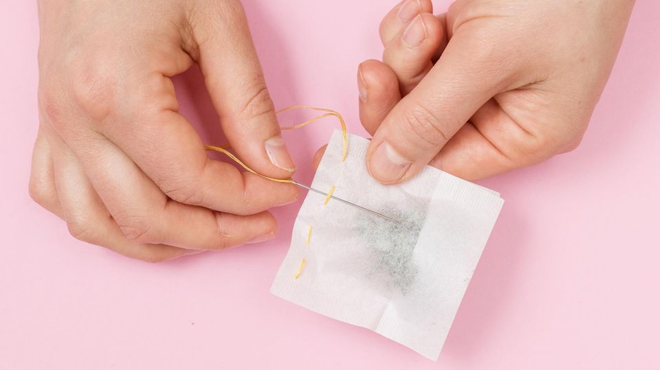 Der Teebeutel wird mit Nadel und Faden zugenäht Der Teebeutel wird mit Nadel und Faden zugenäht