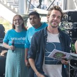 Tobias Krell alias "Cecker Tobi" (2. von rechts) steht mit Moderationskarten und einem Mikrofon hinter der Bühne.