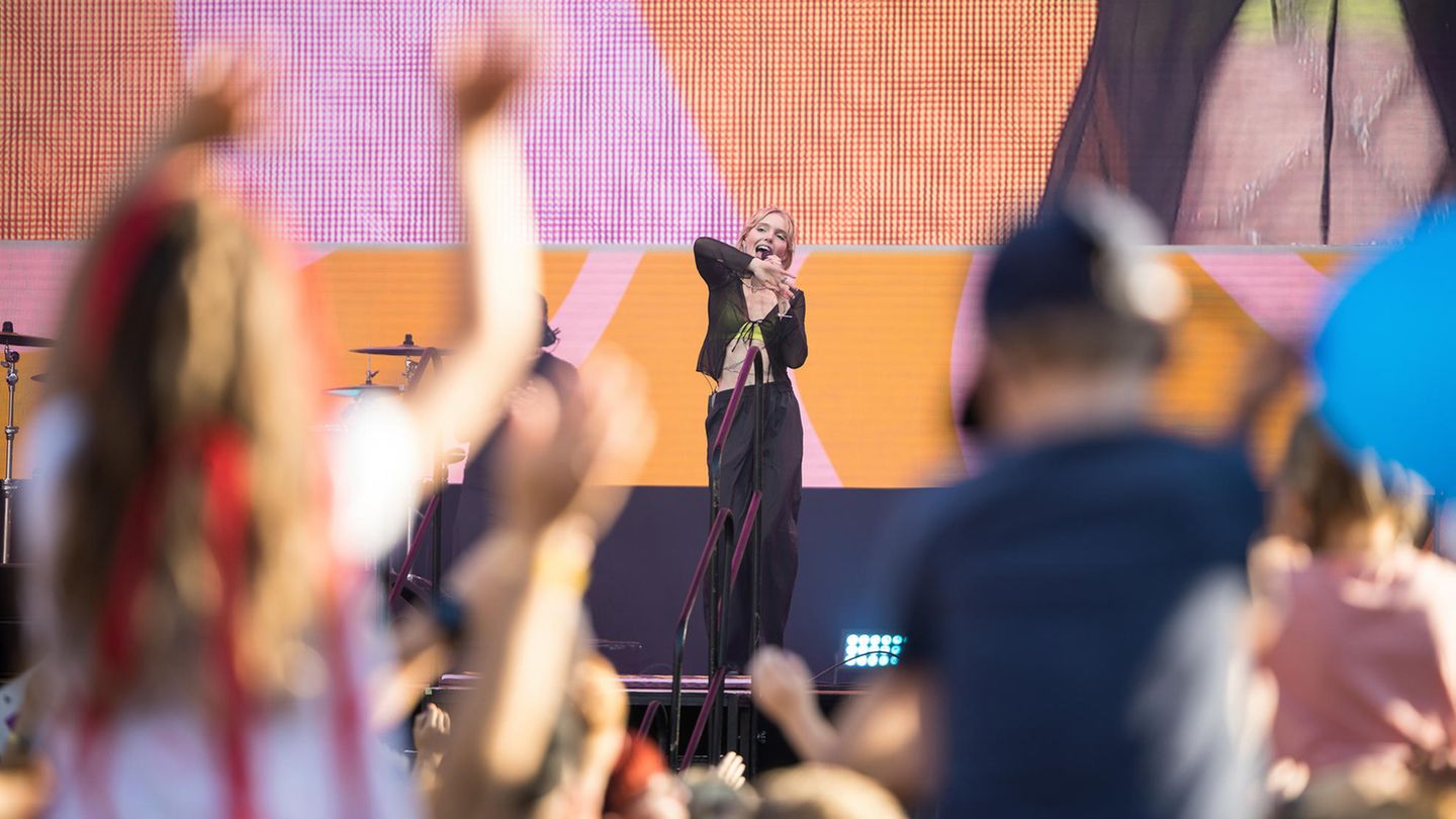 Künstlerin LINA stehr auf der GEOlino LIVE 2022-Bühne. Unscharf angeschnitten sieht man winkende Zuschauerinnen und Zuschauer.