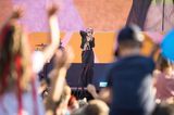 Künstlerin LINA stehr auf der GEOlino LIVE 2022-Bühne. Unscharf angeschnitten sieht man winkende Zuschauerinnen und Zuschauer.