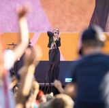 Künstlerin LINA stehr auf der GEOlino LIVE 2022-Bühne. Unscharf angeschnitten sieht man winkende Zuschauerinnen und Zuschauer.