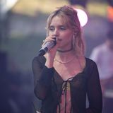 Künstlerin LINA steht auf der Bühne und singt, sie hält ein Glitzer-Mikrofon in der Hand.