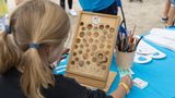 Ein Kind spielt mit einem durchlöcherten Brett und einer Murmel am Stand des Kinderhilfswerks UNICEF.