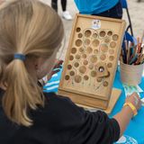 Ein Kind spielt mit einem durchlöcherten Brett und einer Murmel am Stand des Kinderhilfswerks UNICEF.