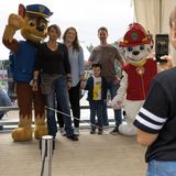 Eine Familie macht ein Foto mit zwei Figuren von Paw Patrol.