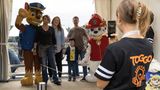 Eine Familie macht ein Foto mit zwei Figuren von Paw Patrol.