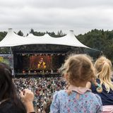 Menschen im Publikum schauen auf die Bühne, auf der Künstler und Künstlerinnen auftreten.