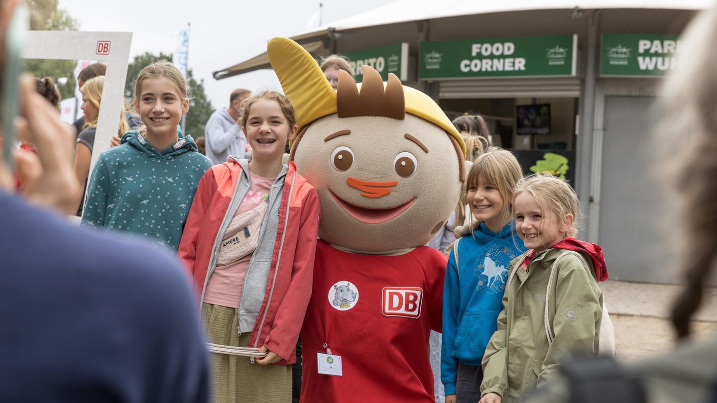 Kinder stehen für ein Foto zusammen mit einem Maskottchen der Deutschen Bahn.
